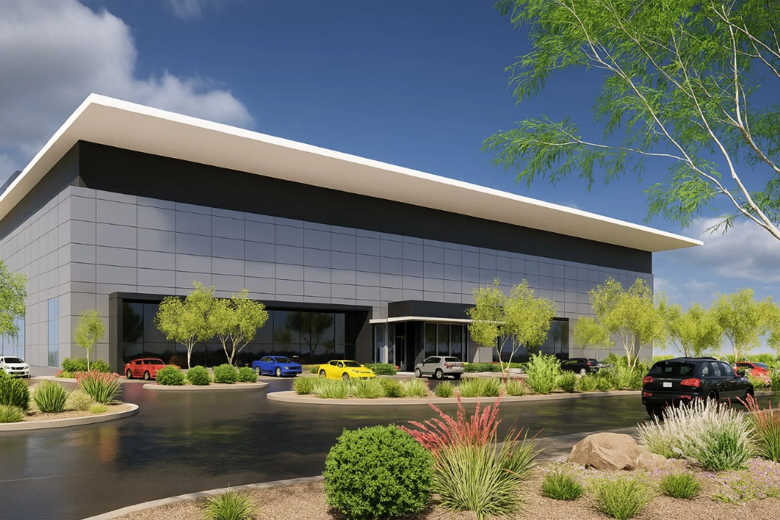 Modern commercial building with dark gray facade, reflective windows, and white roof. Desert landscaping with cars in the foreground.